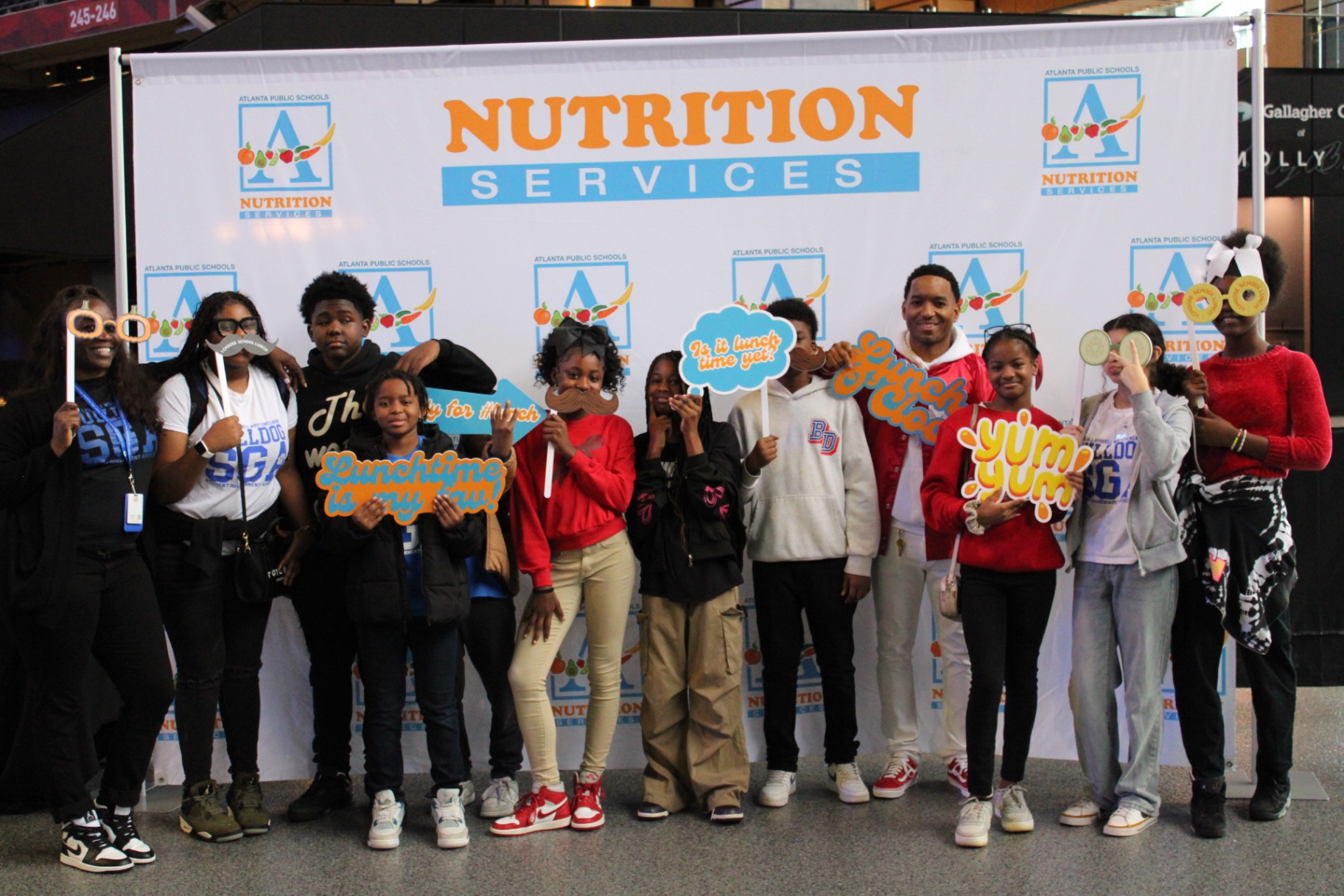 Students from Herman J. Russell West End Academy posing with custom lunch-themed photo props at Mercedes-Benz Stadium